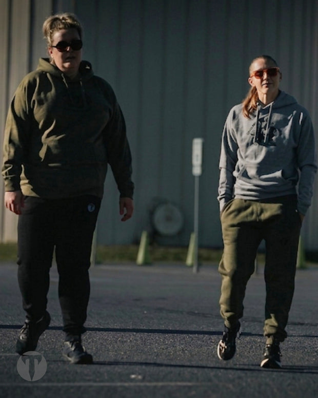 Titan 6 Athletes Nicole Kelly and Kelly Sullivan walking outdoors in front of Spooky Nook sports complex wearing Titan Ethos Citadel Pullover Hoodies.