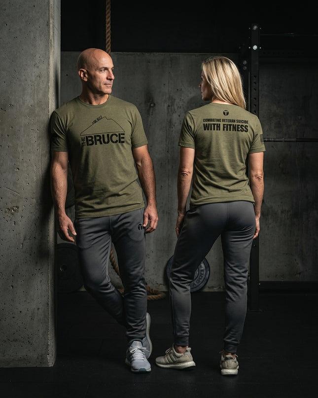 Titan 6 Actual Combatting Veteran Suicide With Fitness Bruce WOD graphic tee with grey joggers in gym environment.