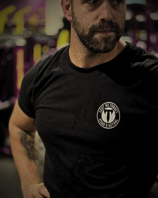 A male Titan 6 Athlete wearing a black shirt printed with the Titan 6 Actual Lest We Forget logo.