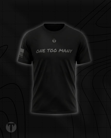 Front view of the Titan 6 Men's Endure T-Shirt in black, featuring the light grey chest graphic "ONE TOO MANY" below a small Titan 6 Icon logo and a monochromatic American flag graphic on the right sleeve.