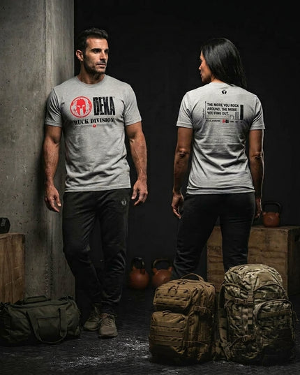 Male and female athletes wearing gray Spartan DEKA Ruck Division graphic t-shirts alongside tactical rucksacks and kettlebells in a training facility.