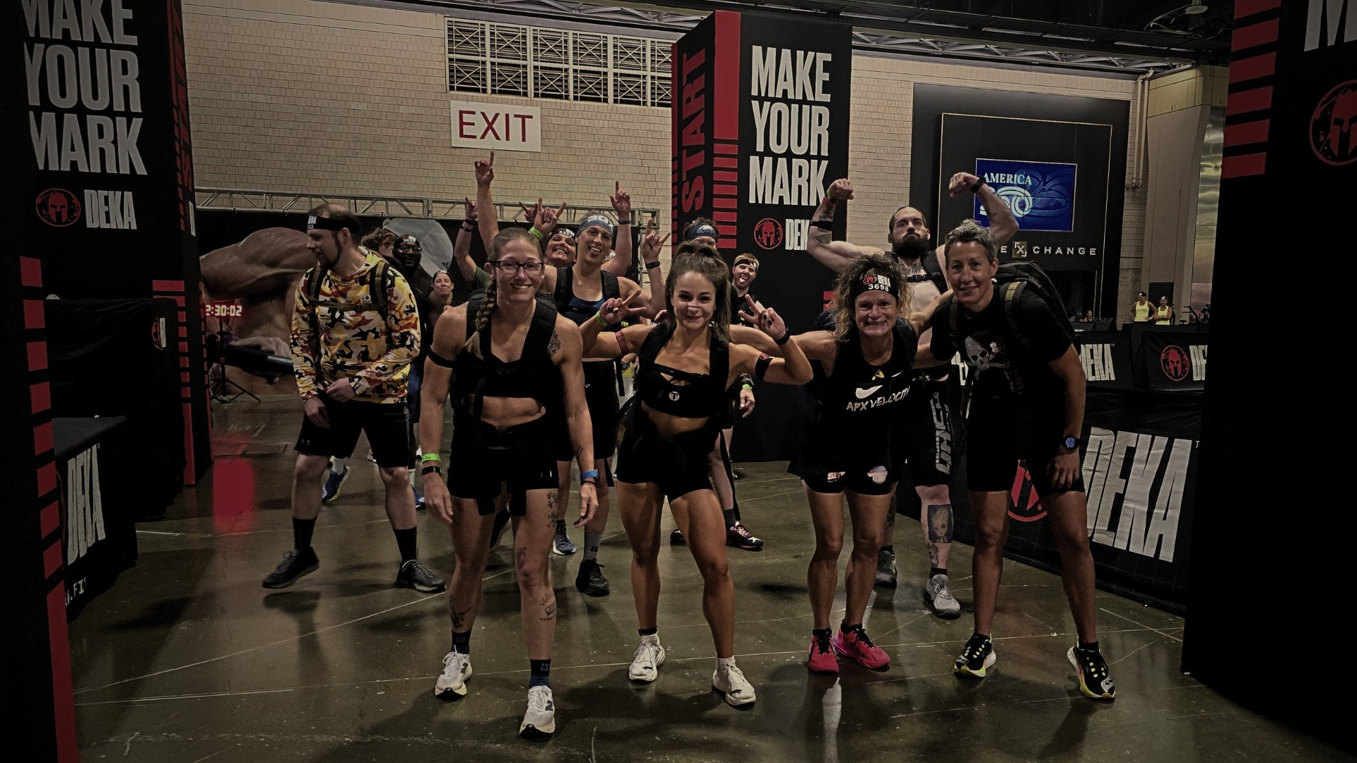 Titan 6 Athletes standing together at the Spartan DEKA FIT Ruck event start line wearing workout apparel and weighted rucksacks.
