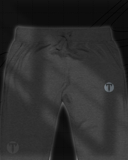 Titan 6 Unisex Garrison Jogger Icon in Charcoal Heather, featuring an elastic waistband with drawstrings and a silver circular "T" logo printed on the upper left thigh.