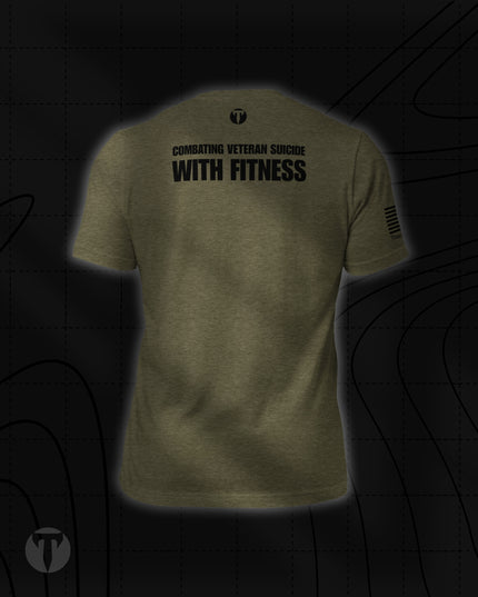Back view of the Titan 6 Unisex Nomad Tee in Olive Green, featuring "COMBATING VETERAN SUICIDE WITH FITNESS" printed across the upper back below a small "T" logo, with an American flag print on the right sleeve.