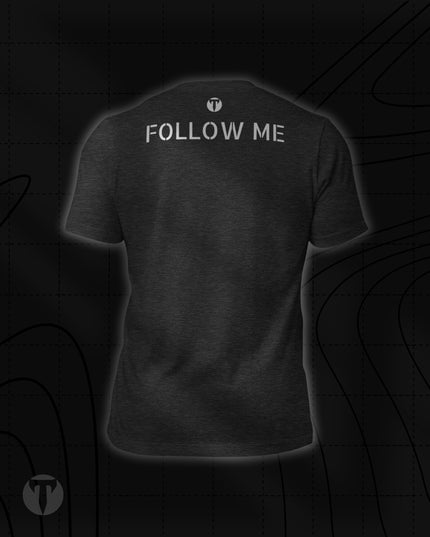 Back view of the Titan 6 Unisex Nomad Tee in Dark Grey Heather, featuring "FOLLOW ME" printed across the upper back in stencil-style silver lettering, with a small silver "T" logo centered above it.