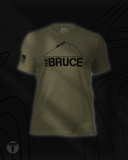Titan 6 Unisex Nomad Tee in Olive Green, featuring "THE BRUCE" graphic with "Hill 937" and a mountain contour line across the chest, plus an American flag patch print on the right sleeve.