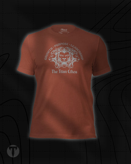 Titan 6 Unisex Nomad Tee in Heather Clay, featuring a silver three-headed lion emblem with "GROWTH • PURPOSE • LEADERSHIP" arched above and "The Titan Ethos" printed below.