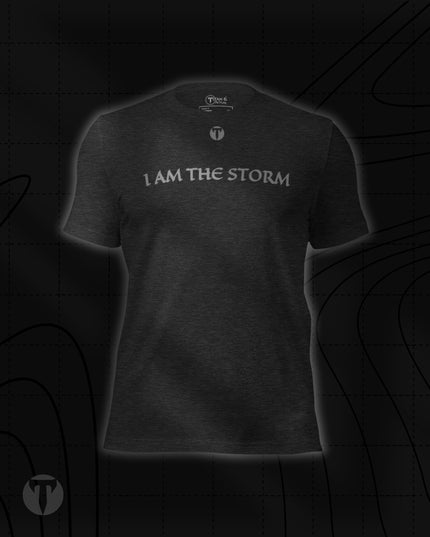 Titan 6 Unisex Nomad Tee in Dark Grey Heather, featuring "I AM THE STORM" printed across the upper chest in a stylized font, with a small silver "T" logo centered above it.