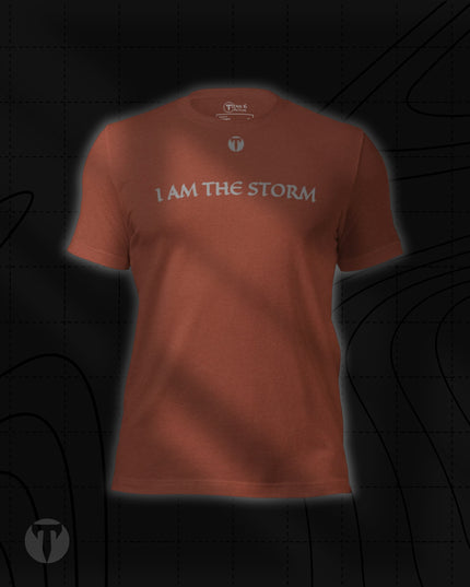 Titan 6 Unisex Nomad Tee in Heather Clay, featuring "I AM THE STORM" printed across the upper chest in a stylized font, with a small "T" logo centered above it.