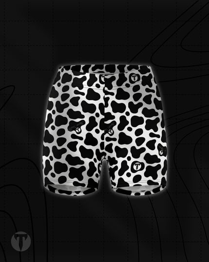 Titan 6 Women's Glide Shorts in Udder Chaos, featuring a black and white cow print pattern with a small white circular "T" logo on the lower left leg.