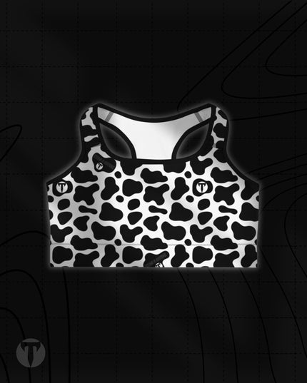 Titan 6 Women's Glide Sports Bra in Udder Chaos, featuring a black and white cow print pattern with a small white circular "T" logo on the right chest.